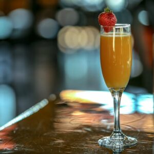 Image of a mimosa with a strawberry on the rim of the glass.
